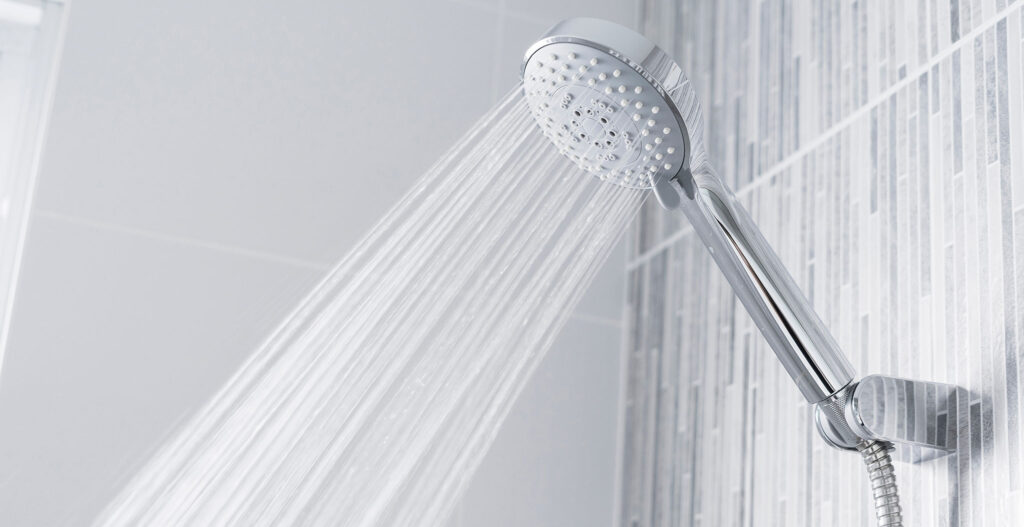 Showerhead with water spraying in a modern tiled bathroom