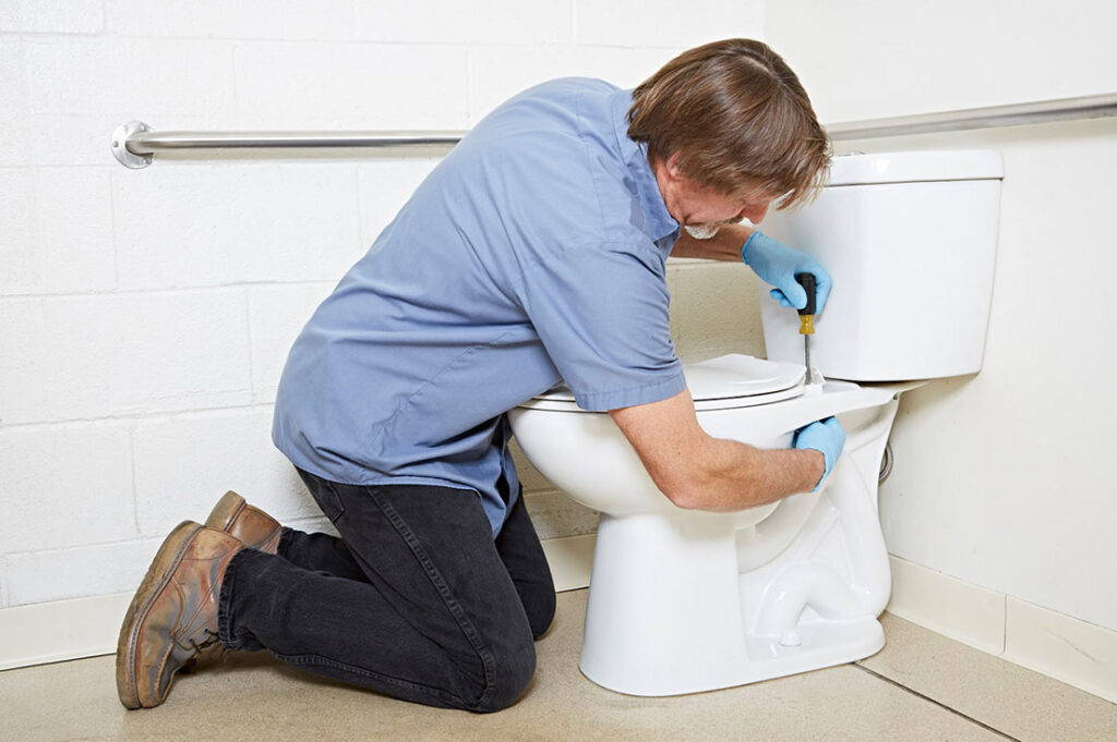 Man fixing a toilet with a screwdriver